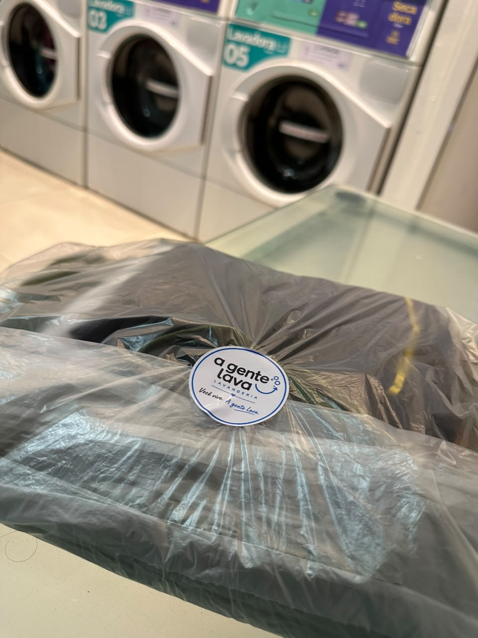 Pacote de roupas embalado com etiqueta da A Gente Lava Lavanderia